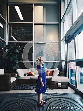 Cute adorable abandoned sad lonely preschool Caucasian little girl child standing alone in mall shop between sliding doors waiting Stock Photo