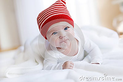 Cute adorable baby child with Christmas winter cap on white background. Happy baby girl or boy smiling and looking at Stock Photo