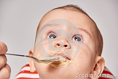 Cute adorable baby eating porridge with a spoonful of the concept of proper nutrition Stock Photo