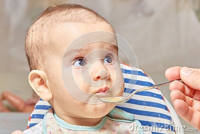 Cute adorable baby eating porridge with a spoonful of the concept of proper nutrition Stock Photo