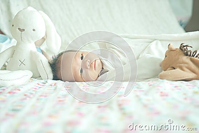 Cute adorable newborn baby boy wrapped or swaddle in a blanket, sleeping and sometime both eyes open in kids bed Stock Photo