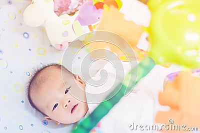 Cute adorable newborn baby playing on colorful toy Stock Photo