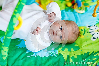 Cute adorable newborn baby playing on colorful toy gym Stock Photo