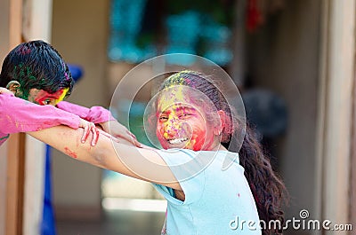 Cute adorable siblings playing with colours during holi festival of colors Indian asian caucasian creative portrait Stock Photo