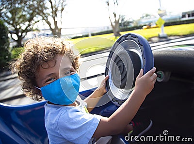 Cute African American child driving a fun go cart ride at an outdoor amusement park Stock Photo