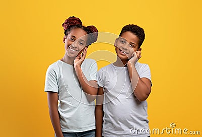 Cute african american siblings sharing earphones, listening to music Stock Photo