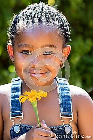 Cute african girl holding orange flower outdoors. Stock Photo