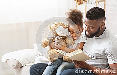 Cute afro family father and daughter reading book at home Stock Photo
