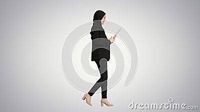 Cute Arabian businesswoman using tablet computer while walking o Stock Photo
