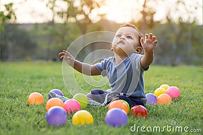 Cute asian baby playing colorful ball in green grass Stock Photo