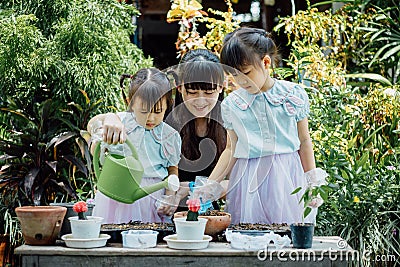 Cute asian child girl helping mother planting or cutivate the plants. Mom and daughter engaging in gardening at home. Happy activi Stock Photo