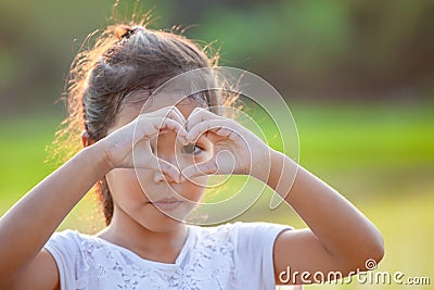 Cute asian child girl making heart shape with hands in the field Stock Photo