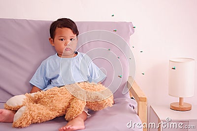 Cute asian child about 2 years old on the sofa in the living room and lots of mosquitoes are biting the little boy, Mosquitoes Stock Photo