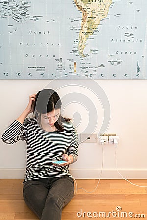Cute asian girl frustrating with phone's battery, charging on the wall Stock Photo
