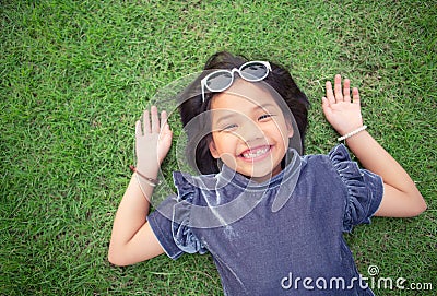 Cute Asian girl laying on Greenery Field Stock Photo