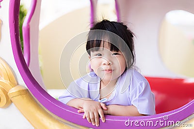 Cute Asian girl looked out of the window of a toy car. Child smiles sweet and bright. Children play in amusement park. Stock Photo
