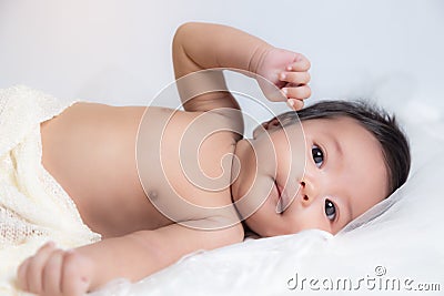 Cute asian infant baby 2 months old, wake up early in morning. Adorable baby Asia girl lay down on bed with blanket. Lovely little Stock Photo