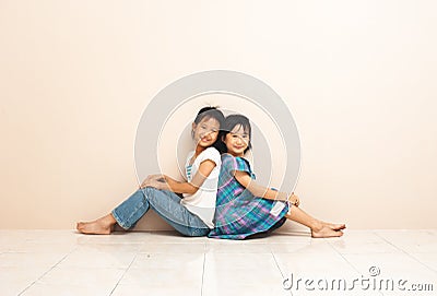 Cute asian siblings sit and touch each other with their backs. Lovely sincere emotions from childhood. Stock Photo