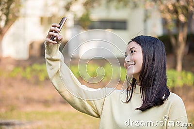 Cute Asian women are using their phones to take selfies and smile happy in the garden at home Stock Photo