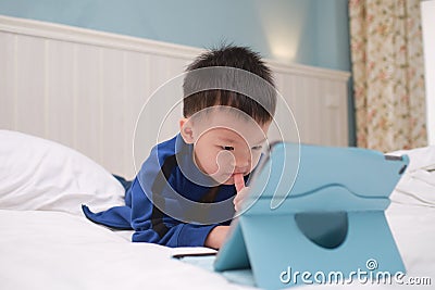 Cute Asian 3 - 4 years old toddler boy child playing game, watching cartoon, using tablet pc computer, Gadget addicted children, Stock Photo