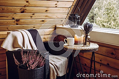 Cute autumn hygge home decor arrangement. Tiny wooden cabin balcony with heather flowers lavender in bottle vase candlelight. Stock Photo