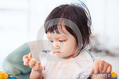 Cute baby asian child girl eating healthy food by herself Stock Photo