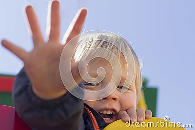 Cute baby boy giving high five to someone. Happy smiling portrait of child, outside. Close-up of adorable kid enjoying Stock Photo