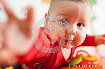 Cute baby boy stretches out his hand towards the camera in front and tries to reach and touch the toy Stock Photo