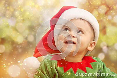 Cute baby in Christmas costume against blurred lights. Magical festive atmosphere Stock Photo