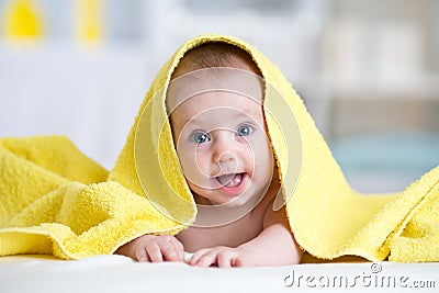 Cute baby covered with a bath towel lying on tummy in the bathroom Stock Photo