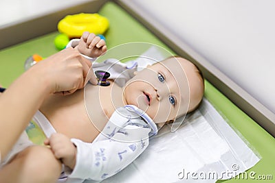 Cute baby at doctor`s cabinet. Pediatrician making examination of child with stethoscope. Smiling healthy kid. Children Stock Photo