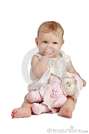 Cute baby with doll sucking thumb in sleeveless sundress Stock Photo