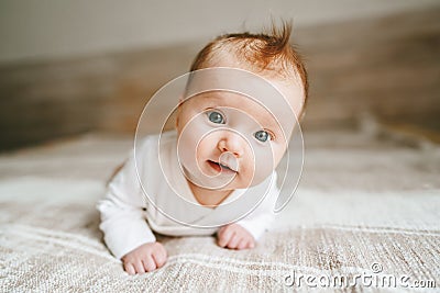 Cute baby ginger hair close up crawling on bed smiling Stock Photo