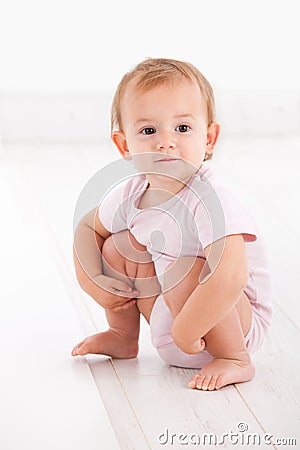 Cute baby girl crouching on floor Stock Photo