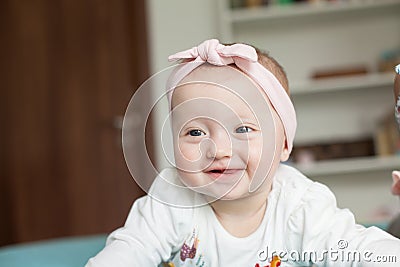 Cute baby girl with hairband ribbon, smiling, laughing. Adorable child having fun at home, happiness concept Stock Photo