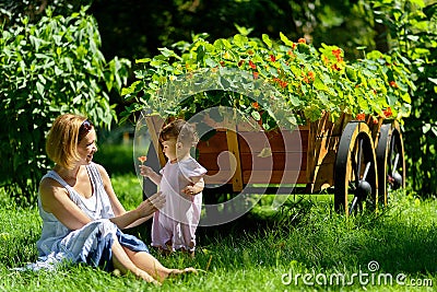 Cute baby girl with mother in a garden with flower Stock Photo