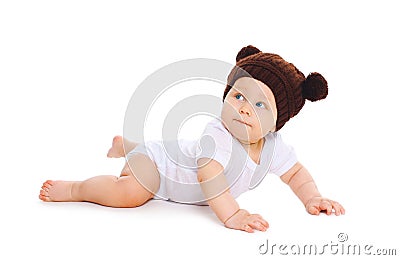 Cute baby in knitted brown hat with ears bears crawls on white Stock Photo