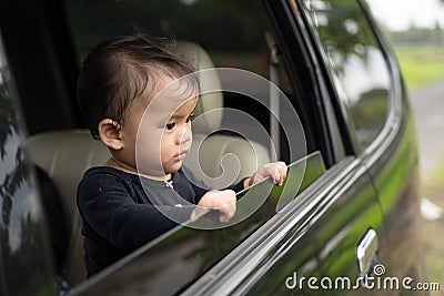 Cute baby looks outside while standing in the car with the windows open Stock Photo