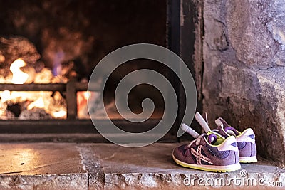 Cute purple sneakers drying on the heat of a fire place Stock Photo