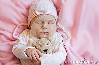 Cute baby sleeping with teddy bear toy on pink soft bed at home Stock Photo