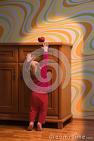 Persistance conceptual. Baby nutrition concept. Toddler trying to reach red apple. Happy meal for children. Fresh fruits Stock Photo