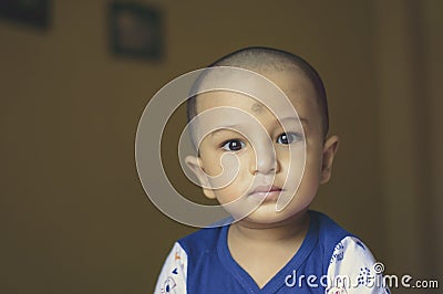 Cute bald indian baby boy in blue and white shirt looking away. Head and shoulder shot. Close up Stock Photo