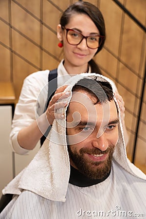 Cute barber dries the hair of client with soft towel Stock Photo