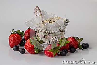 Cute basket with strawberries blueberries and oats white background Stock Photo