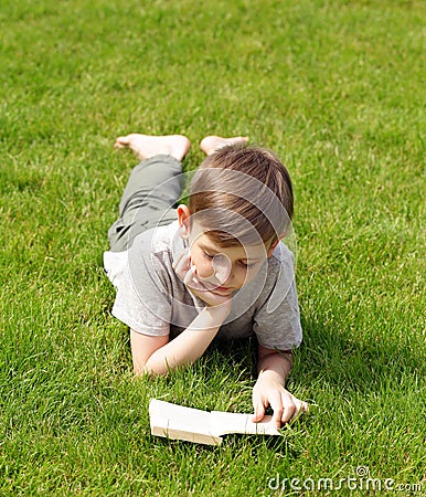 Cute blond boy reading a book in a park Stock Photo