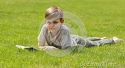 Cute blond boy reading a book in a park Stock Photo