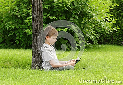 Cute blond boy reading a book in a park Stock Photo