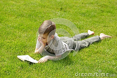 Cute blond boy reading a book in a park Stock Photo