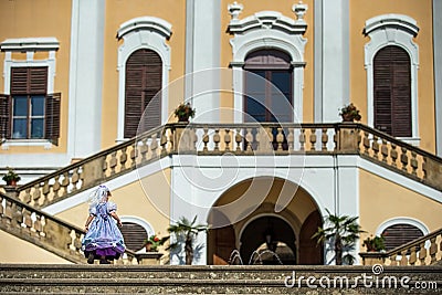 Cute blond curly girl dressed up as princess in the garden of ancient castle, beautiful small girl in blue long dress, fairy tale Stock Photo