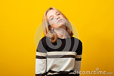 Cute blond teen girl. Studio image of smiling young girl on yellow background Stock Photo
